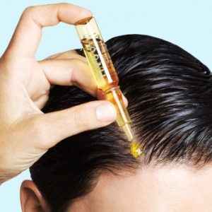 aplicando ampolla en un pelo negro liso